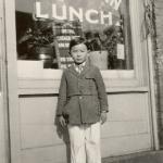 Immigrant Boy Standing in Front of a Local Business