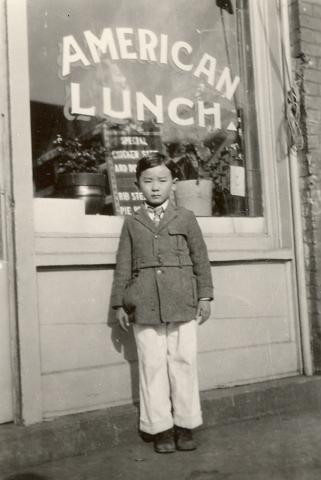 Immigrant Boy Standing in Front of a Local Business