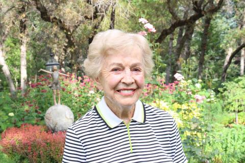 A portrait of Barbara Lindquist Tanner with a garden scape background. Photo was taken on August 22, 2019